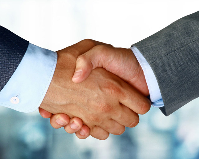 two men in suits shaking hands after completing a business deal